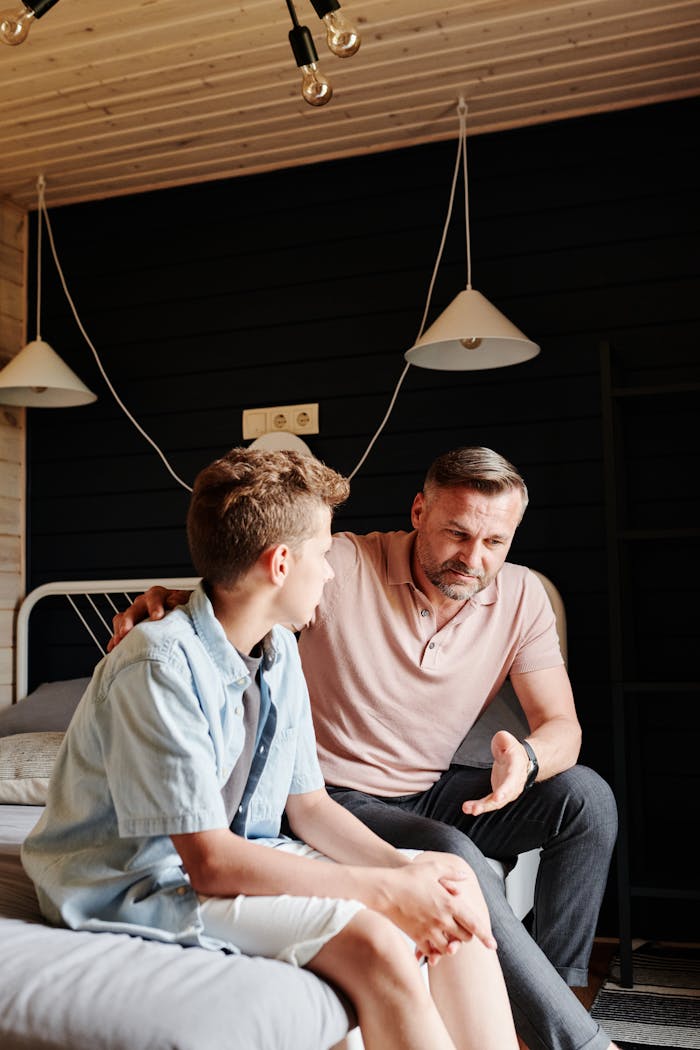 Father and son having a meaningful talk in a cozy bedroom setting.